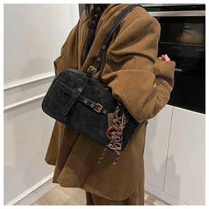 Detail view of black suede shoulder bag with buckle straps and a Sunny charm decoration