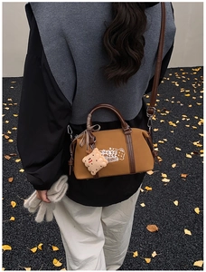 Detail view of retro Boston bag with cute cookie plush pendant on an autumn street