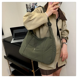 Close-up of army green nylon tote bag with metal snap button pocket and adjustable strap