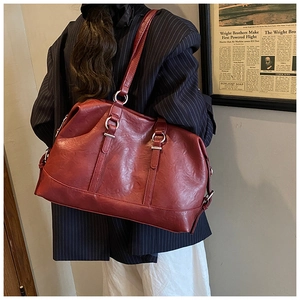 Detail view of deep red vintage tote bag with elegant metallic rings and slim shoulder straps