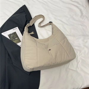 Detail view of beige nylon tote bag showing adjustable wide shoulder strap and snap front pocket