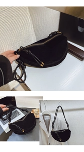 Detail view of black suede hobo bag featuring a knotted wide shoulder strap and tassel zipper