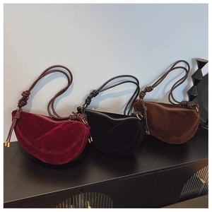 Detailed view of suede crescent bags in burgundy, black, and brown with knotted straps