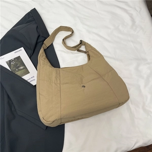 Detail of khaki quilted nylon tote bag with wide shoulder strap on a white bedding background
