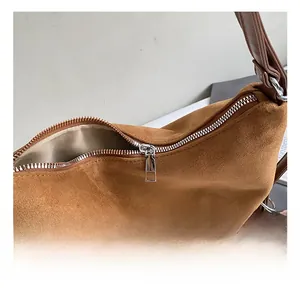 Detail of silver metal zipper and smooth lining on brown suede shoulder bag