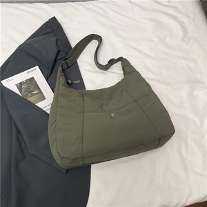 Detail of olive green quilted puffer tote bag featuring metal snap button and strap