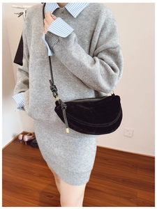 Detail of minimalist black suede crescent bag with leather knotted shoulder strap on model