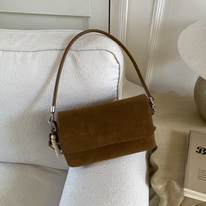 Detail of a brown suede shoulder bag featuring precise stitching and a wooden bead tassel