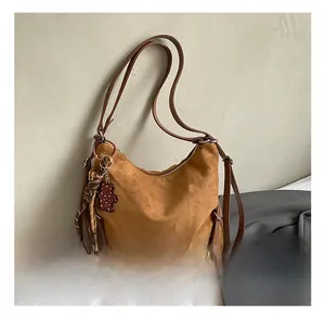 Detailed close-up of brown suede tote bag with bear charm and branded ZSKC logo