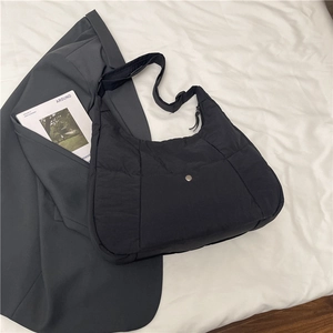 Close-up of black quilted nylon tote bag with square pattern texture and top zipper