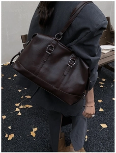 Detail of dark brown vintage tote bag with metal rings on autumn ginkgo leaves background
