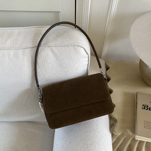 Macro detail of dark brown suede handbag texture with large white bead charm accessory