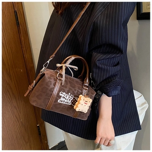 Detail of dark brown vintage Boston bag with plush cookie charm and ribbon handle