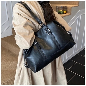 Close-up of a large black tote bag with silver metal rings and fine leather texture