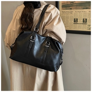 Detail of black faux leather tote bag with silver ring hardware and long zipper accents