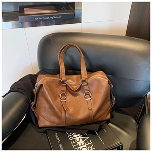 Detail of the brown textured leather tote with silver metal rings and double handles