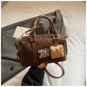 Detail of vintage brown Boston bag with letter embroidery and cute biscuit charm