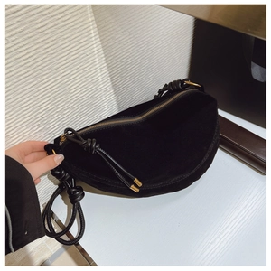 Close-up of black suede crescent bag featuring braided rope strap and gold hardware