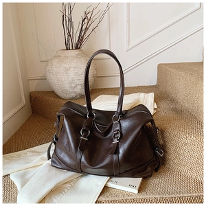Detail of dark brown vintage tote bag with elegant silver ring hardware on warm textured background