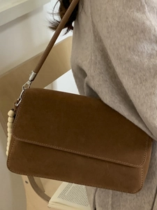 Brown faux suede rectangular shoulder bag with side bead charms shown on a model