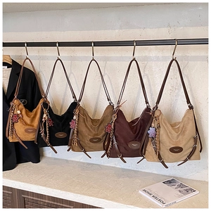 Detail view of retro hobo bags in five colors with soft suede texture and bear pendant