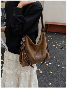Detailed macro of dark brown suede hobo bag featuring woven tassels and leather brand tag