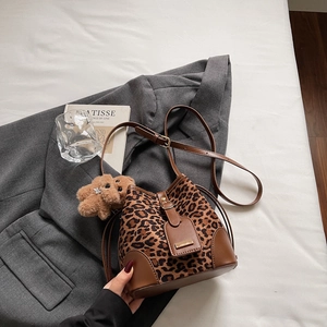 Detail of leopard print bucket bag with brown leather trim and a cute plush bear charm
