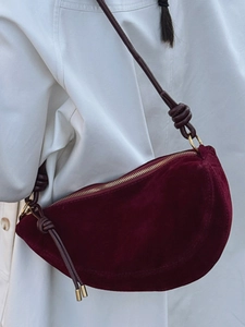 Elegant burgundy suede half-moon shoulder bag with minimalist knot strap design