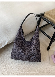 Détail du sac hobo à motif léopard avec bandoulière en cuir sur un tapis blanc