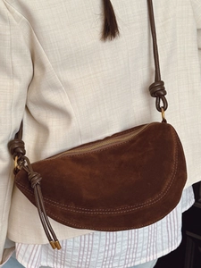Dark brown suede crescent crossbody bag with minimalist knot strap detail and matte finish
