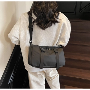 Detail of black tactical nylon messenger bag with buckle straps and adjustable shoulder strap