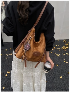 Detail view of large brown suede hobo bag with adjustable strap and leopard bear charm