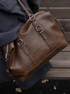 Retro brown leather tote bag with silver hardware for women in an autumn street setting