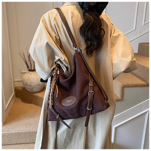 Detail view of large dark brown suede tote bag featuring metallic hardware and side drawstring