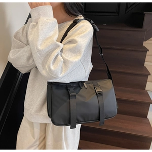 Detail of black tactical crossbody bag showing buckles and durable nylon fabric material