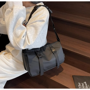 Detail of black waterproof crossbody bag featuring dual buckle straps and adjustable wide strap