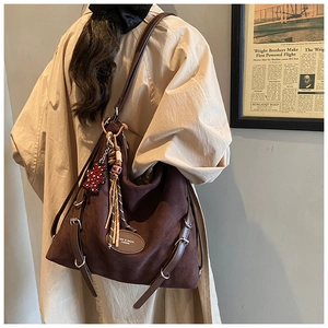 Brown suede hobo tote bag styled with beige trench coat and vintage leopard bear charm