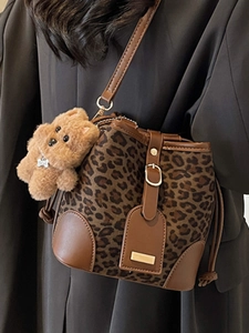 Chic leopard print bucket bag with brown leather trim and cute plush bear charm