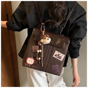 Detail of vintage brown leather backpack featuring cute cartoon patches and plush charms
