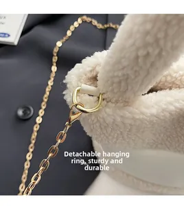 Détail de l'anneau doré amovible et de la chaîne sur un sac seau en peluche blanche