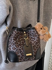 Chic leopard print bucket bag with black leather trim and cute puppy charm on a model