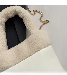 Détail de la texture pelucheuse en laine d'agneau et du cuir grainé blanc sur le sac seau