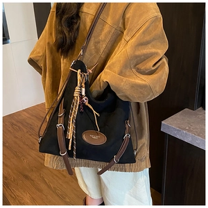Detail of black Hobo bag featuring brown leather straps and woven knot pendant