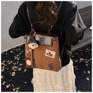Detail of vintage brown backpack featuring cartoon patch and cute plush bear accessory