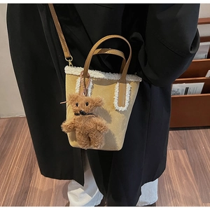 Dettaglio mini borsa a secchiello in camoscio giallo con bordo in pelliccia e orso