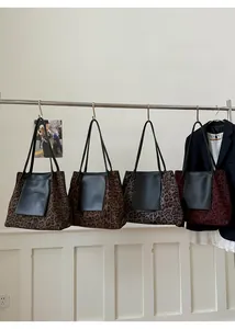Detail view of large leopard print tote bags in four colors hanging on a rack