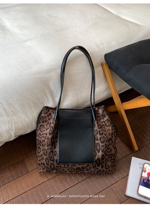 Close-up of leopard print tote bag with a black leather pocket in a minimalist home setting