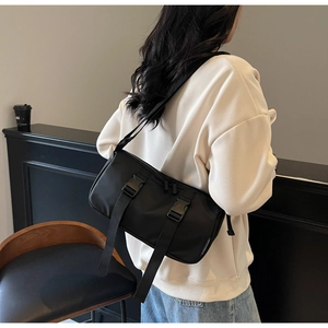 Detail of black nylon crossbody bag with buckle straps and woven label on a model