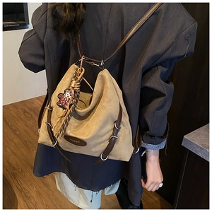 Detail of vintage khaki suede backpack featuring leather straps and leopard floral charm