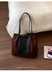 Detail of red leopard print bucket tote bag with black leather patchwork on wood floor